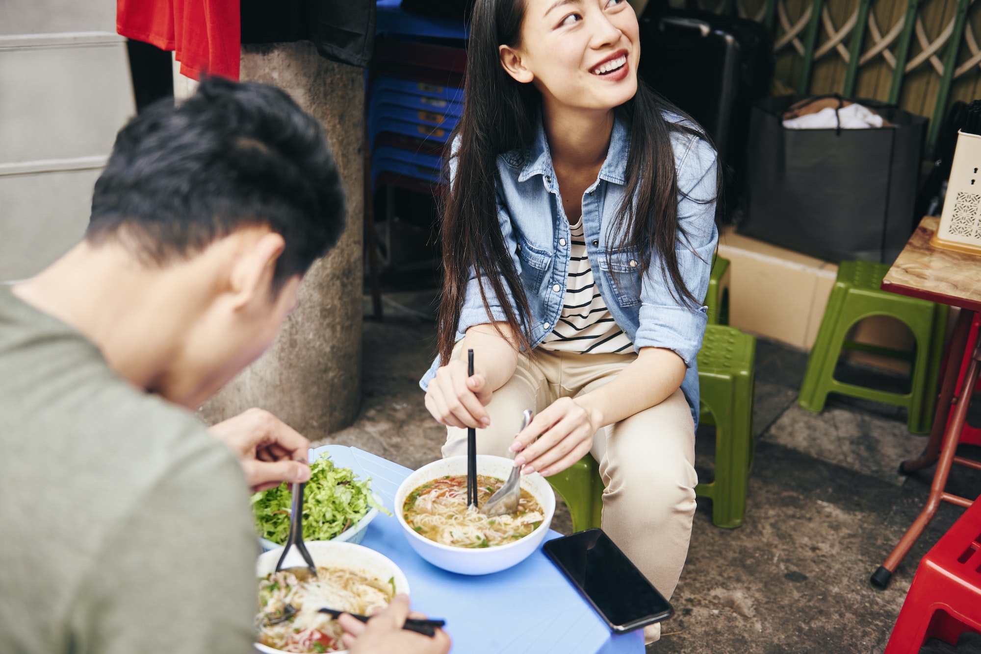 Close up of couple eating pho soup in the city