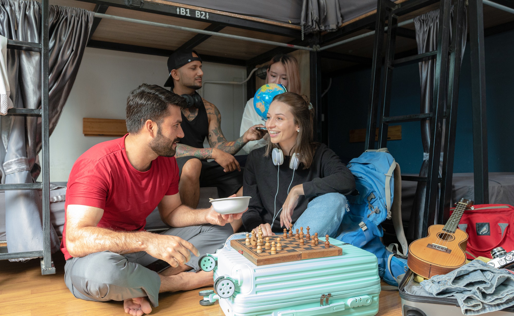 Groups of travelers of different nationalities having fun in the hostel.