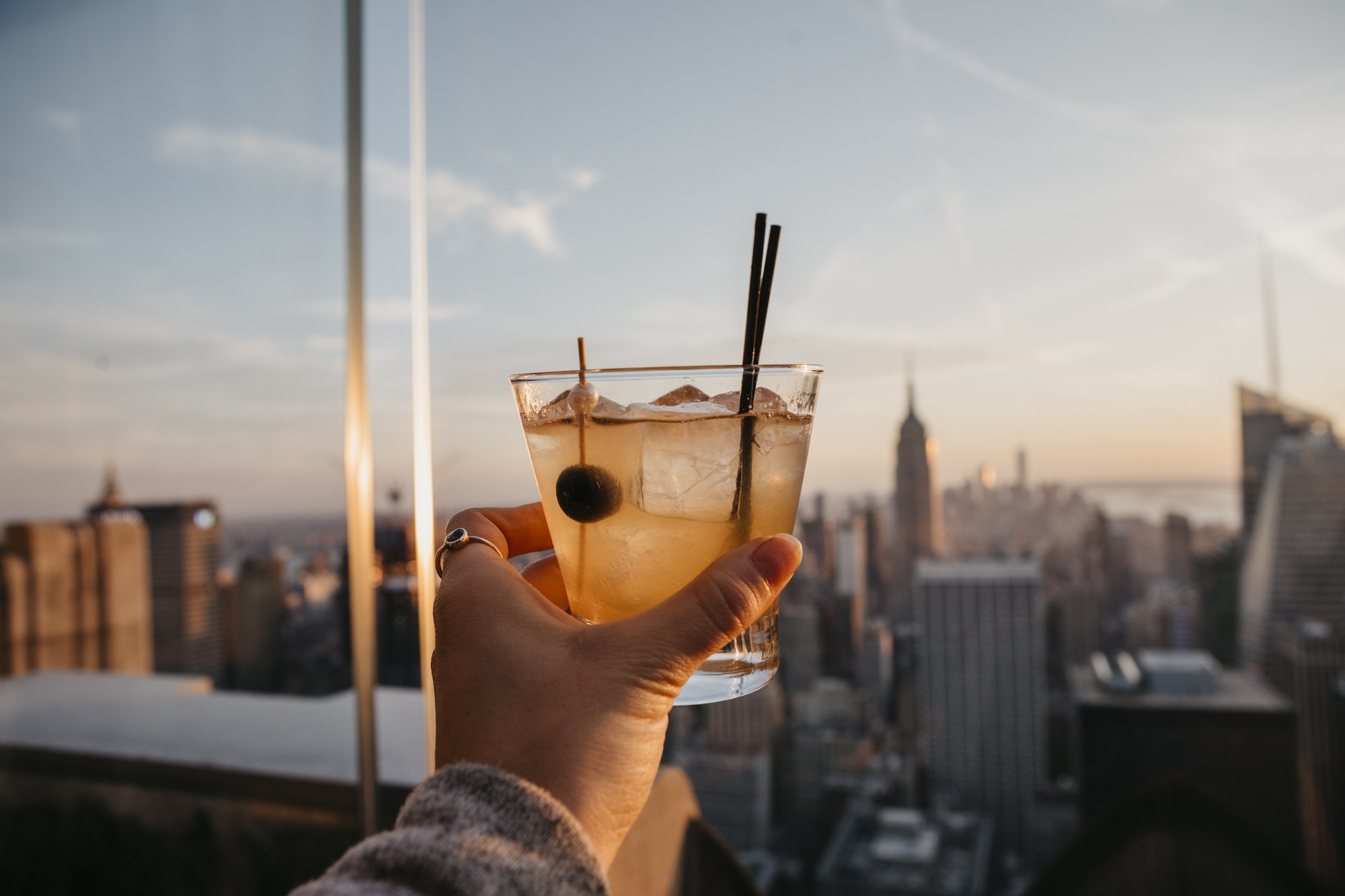USA, New York, New York City, hand with cocktail glass at sunrise
