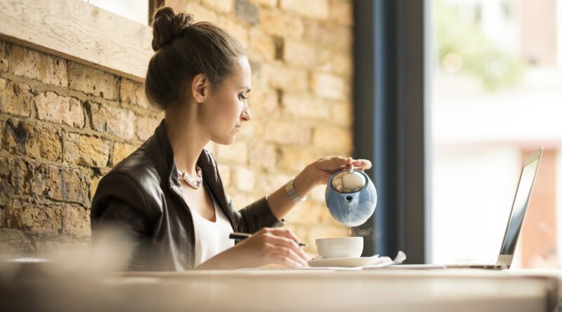 Young businesswoman pouring tea in cafe