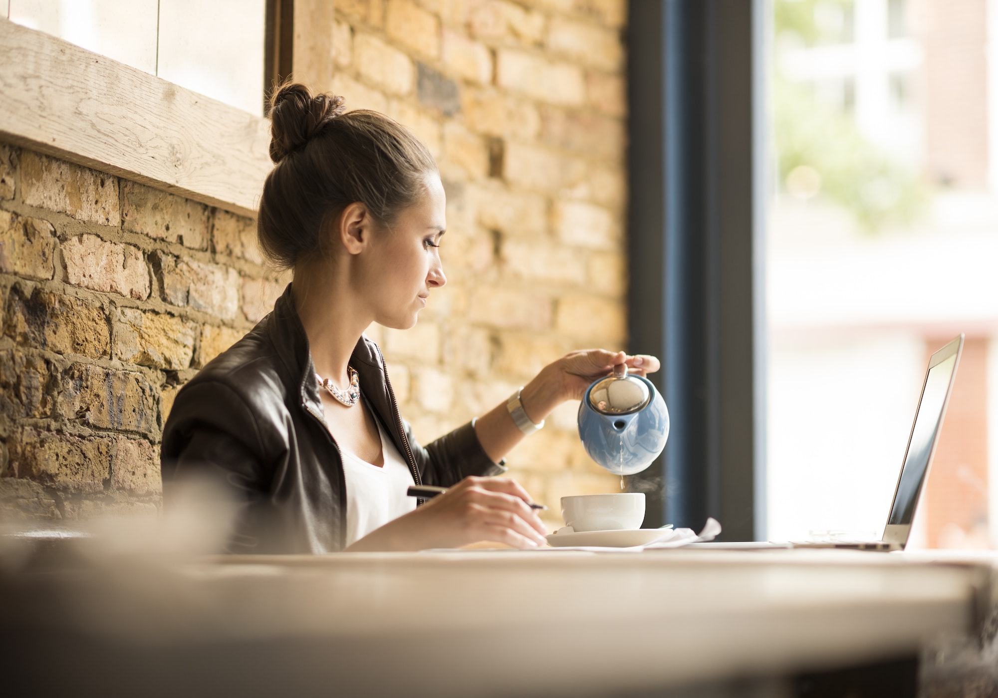 Young businesswoman pouring tea in cafe